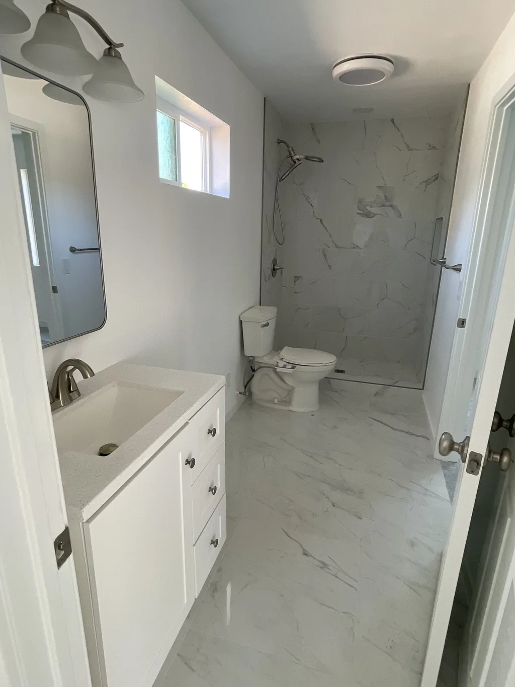 Finished bathroom with a vanity, mirror, toilet and tiled walk-in shower