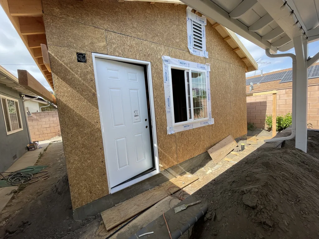 Exterior wall sheathing with a new entry door and window on a detached unit