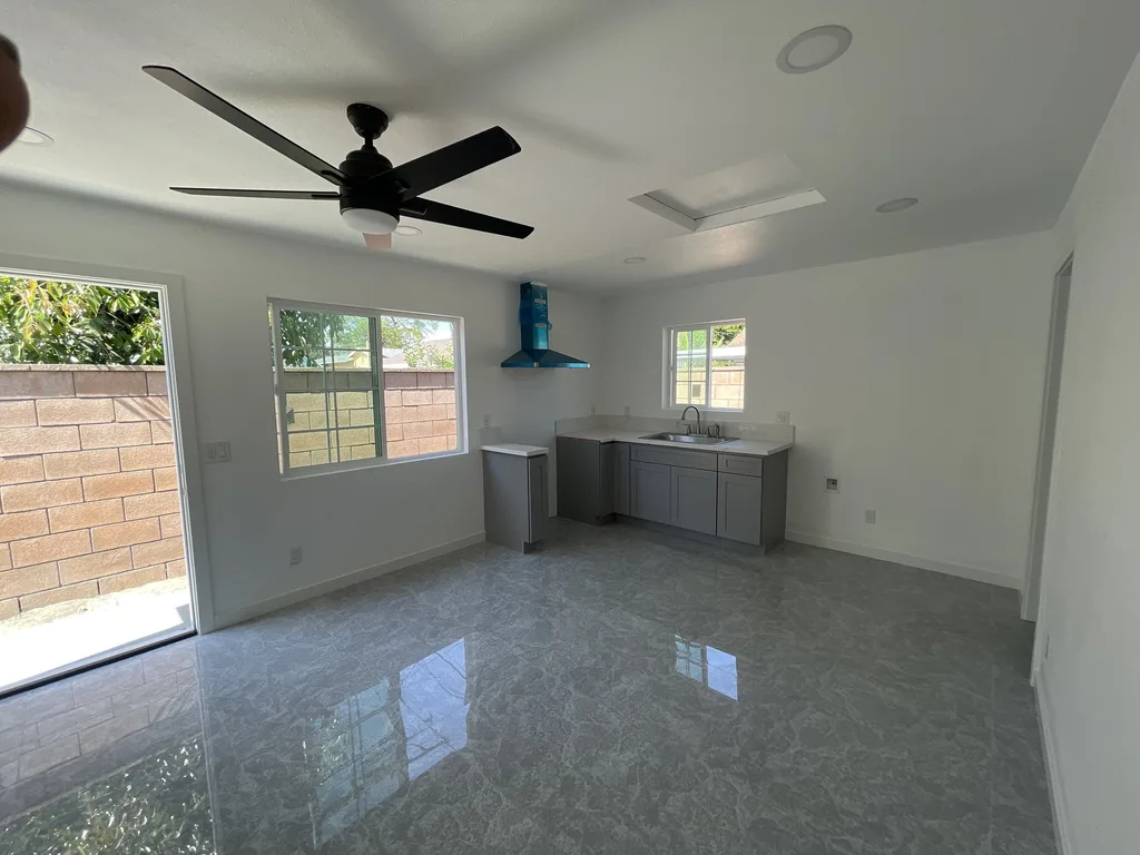 Finished open living space with a kitchenette, ceiling fan, skylight and tile floor