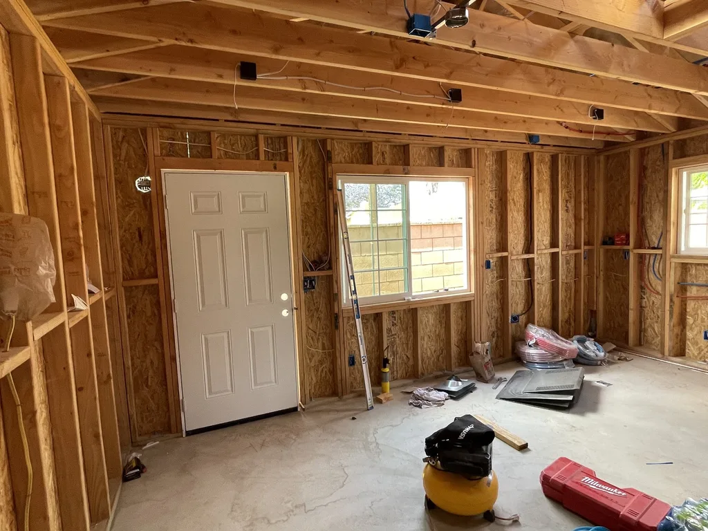 Interior stud framing, rough wiring and open ceiling joists inside a detached unit