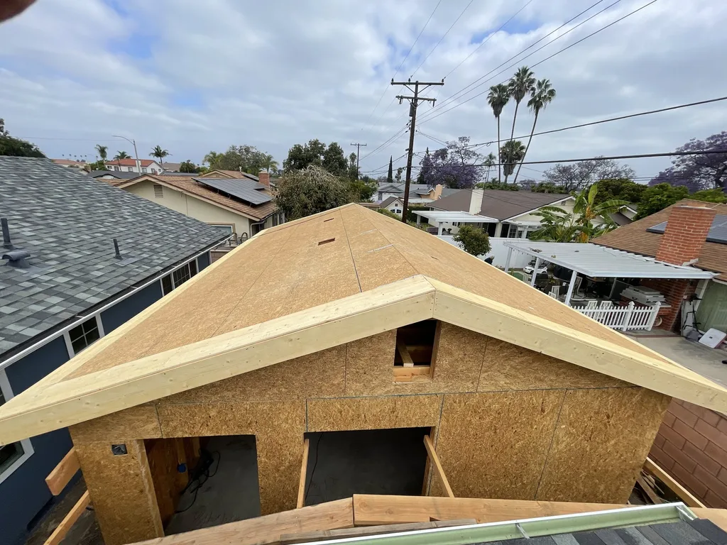 Roof sheathing and ridge framing going on above a detached backyard accessory dwelling unit